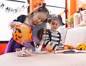 Adorable boy and girl having halloween party holding candies at home