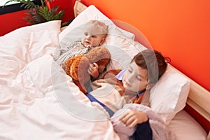 Adorable boy and girl hugging teddy bear sleeping on bed at bedroom