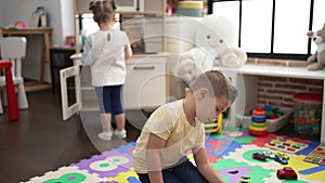 Adorable boy and girl playing with play kitchen and car toys at kindergarten