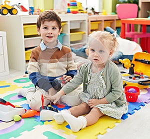 Adorable boy and girl playing supermarket game sitting on floor at kindergarten