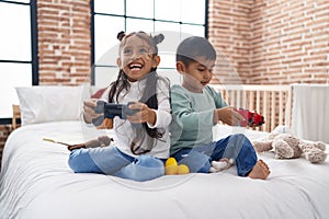 Adorable boy and girl playing video game sitting on sofa at bedroom