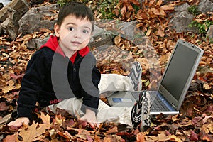 Adorable Boy In Leaves with Laptop