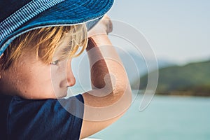 Adorable boy looking to the blue sea from yacht board in sunny day