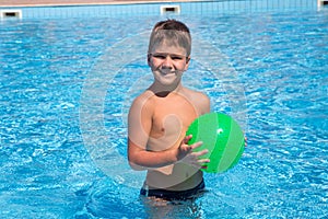 Adorable boy playing with ball in the pool