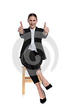 Businesswoman sitting with crossed legs and making double ok sign