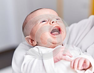 Adorable caucasian baby crying on mother arms at home