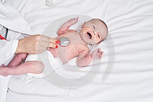 Adorable caucasian baby having heart examination with stethoscope crying at bedroom