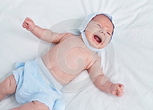 Adorable caucasian baby lying on bed crying at bedroom
