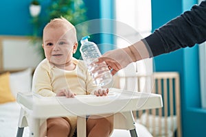 Adorable caucasian baby smiling confident sitting on highchair at bedroom