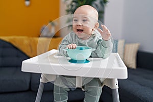 Adorable caucasian baby smiling confident sitting on highchair at home