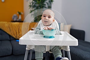 Adorable caucasian baby smiling confident sitting on highchair at home