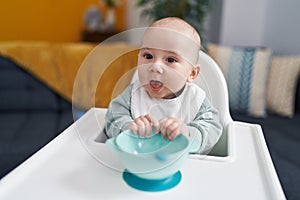 Adorable caucasian baby smiling confident sitting on highchair at home