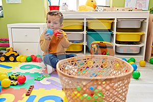 Adorable caucasian boy smiling confident playing with balls at kindergarten