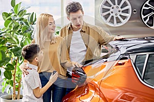Adorable caucasian family with child in cars showroom
