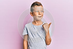 Adorable caucasian kid wearing casual clothes pointing thumb up to the side smiling happy with open mouth