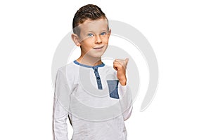 Adorable caucasian kid wearing casual clothes smiling with happy face looking and pointing to the side with thumb up