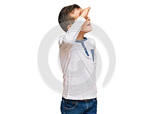 Adorable caucasian kid wearing casual clothes very happy and smiling looking far away with hand over head