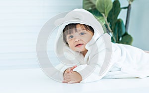 Adorable caucasian little baby daughter girl, wearing cute white bathrobe, taking bath in morning, crawling on floor with copy