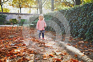 Adorable cheerful toddler girl running in Tuileries garden in Paris