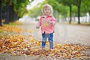 Adorable cheerful toddler girl running in Tuileries garden in Paris