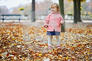 Adorable cheerful toddler girl running in Tuileries garden in Paris, France