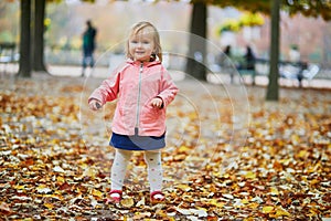 Adorable cheerful toddler girl running in Tuileries garden in Paris, France