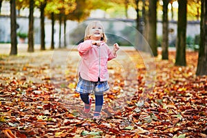Adorable cheerful toddler girl running in Tuileries garden in Paris, France