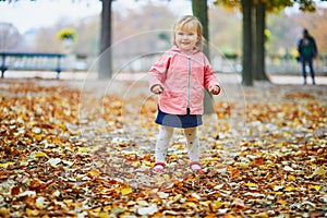 Adorable cheerful toddler girl running in Tuileries garden in Paris
