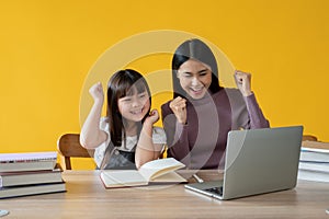 An adorable and cheerful young Asian girl enjoys studying an online lesson with her private tutor