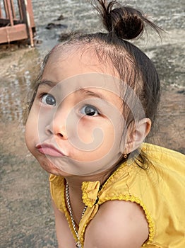 Adorable child Asian woman playing outdoor, happy cute little girl with funny face and looking to camera.