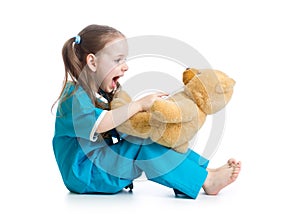 Adorable child dressed as doctor playing with teddy bear