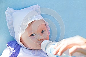 Adorable child girl with infant formula in bottle drinking milk