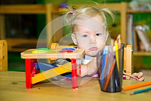 Adorable child girl playing with educational toys in nursery room. Kid in kindergarten in Montessori preschool class.