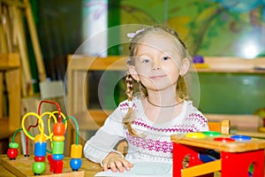 Adorable child girl playing with educational toys in nursery room. Kid in kindergarten in Montessori preschool class.