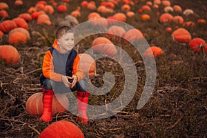 Adorable child having fun with pumpkin on pumpkinpatch on farm.
