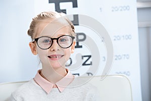 adorable child looking at camera in glasses at oculist