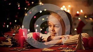 Adorable child looking at candles and wooden toys on table, Christmas decoration