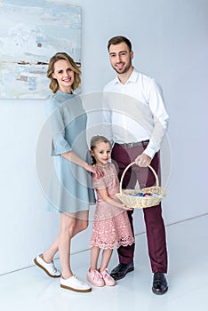 Adorable child and parents with colored eggs