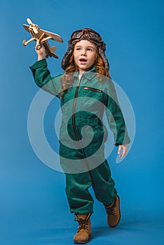 adorable child in pilot costume with wooden plane toy