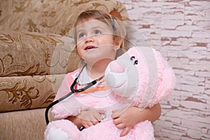 Adorable child playing doctor or nurse with plush toys at home