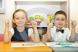 Adorable children boy and girl draws a brush and paints in nursery room. Kid in kindergarten in Montessori preschool class.