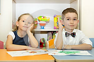 Adorable children boy and girl draws a brush and paints in nursery room. Kid in kindergarten in Montessori preschool class.