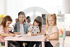 Adorable children drawing together at table. Kindergarten playtime activities