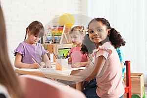 Adorable children drawing together at table. Kindergarten playtime activities