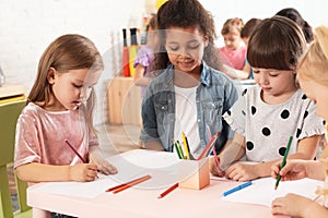 Adorable children drawing together at table. Kindergarten playtime activities