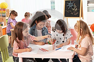 Adorable children drawing together at table. Kindergarten playtime activities