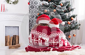 Children in santa hats near christmas tree, wait for holidays photo