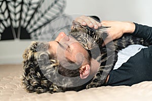 Adorable close up shot of man sleeping with his cat on the bed while holding him with love