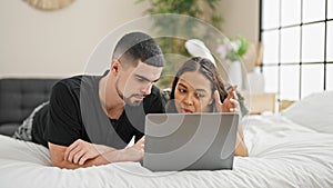 Adorable couple smiling and relaxing at home, lying in bed chatting and enjoying a lovely video call in their cosy, beautifully