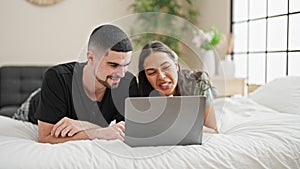 Adorable couple smiling and relaxing at home, lying in bed chatting and enjoying a lovely video call in their cosy, beautifully